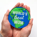 The words 'World's Best Mum' is printed on top of a world map on a coaster to make a useful Mother's Day gift